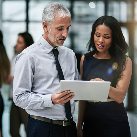 Shot of two professional coworkers using a digital tablet together at work